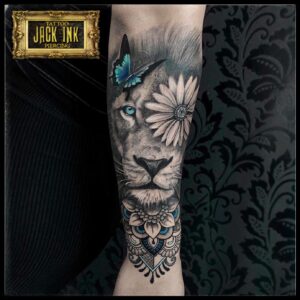 Tatuaj cap de leu cu floare si fluture color pe antebrat